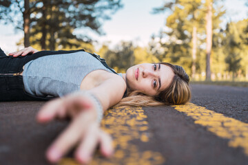 Portrait of a beautiful teenage girl lying on the road.