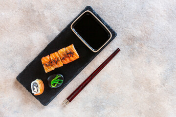 Japanese sushi served on black stone cutting board. Top view, close up on dark background.