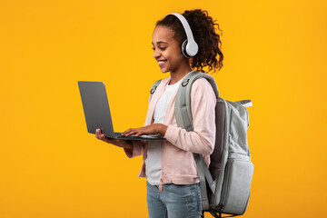 Black girl wearing headset standing with laptop at studio
