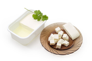 Feta cheese on glass saucer and in container with brine
