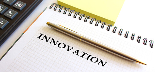 Notepad with text INNOVATION, next to it lies a calculator. Business concept.