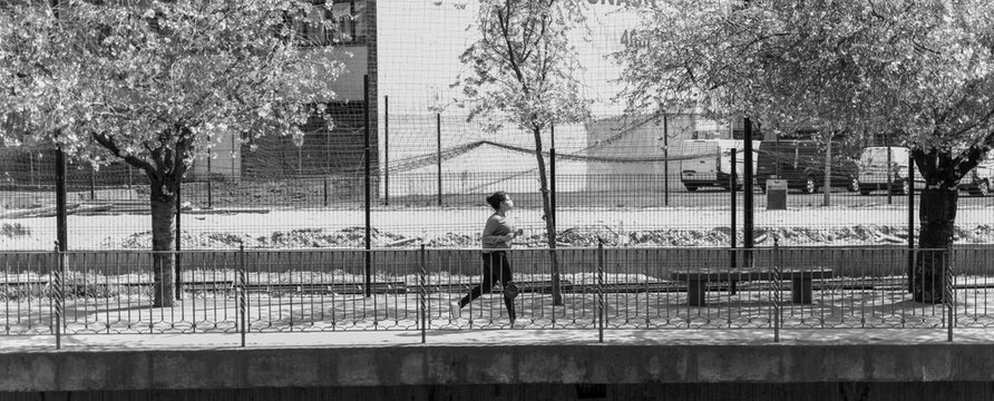 Horizontal black and white image of African American woman jogging through the park.
