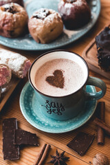 turquoise cup of hot coffee on grey background with cinnamon sticks and christmas decorations