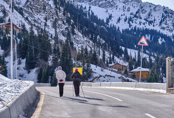 Group of unrecognizable tourists are moving along a mountain road; tourism and travel concept