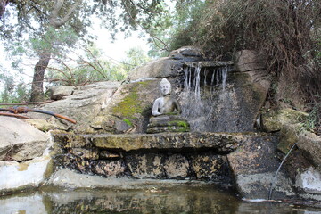 estatua de buda en pequeño estanque con catarata