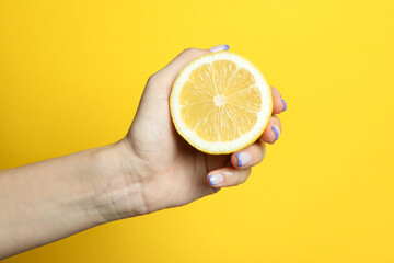 Female hand hold lemon on yellow background