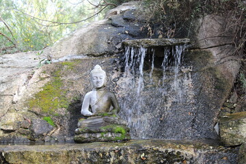 estatua de buda en pequeño estanque con catarata