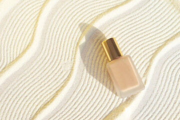   make up foundation bottle with sunscreen  on sand textured background. Cosmetic products  with spf. UV protection concept. Copy space