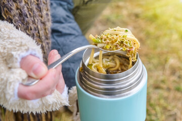 Warm food in a thermos standing on the grass - obrazy, fototapety, plakaty