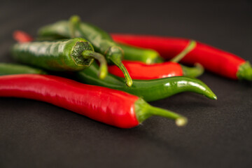 Black and red peppers on black background