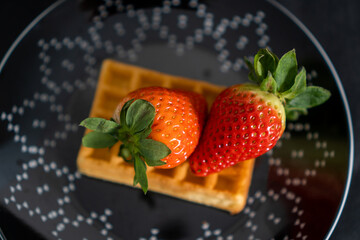 waffle with strawberries on a black plate