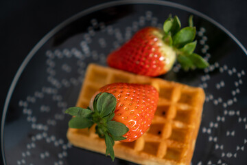 waffle with strawberries on a black plate