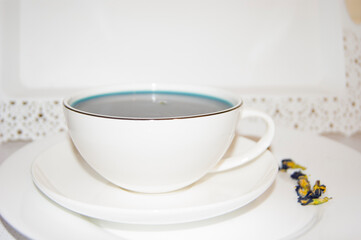 The mood color is blue - blue tea in a white mug, which stands on a white saucer and a white tray.