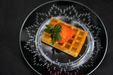 waffle with strawberries on a black plate