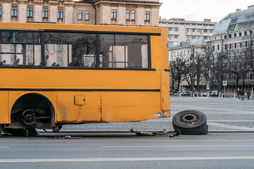 Fototapeta na wymiar City bus with broken wheel stands on urban road.