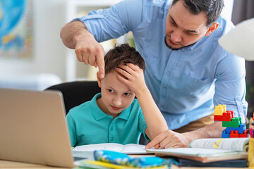 caring father helps his son with homework, using a laptop during distance learning. A parent explains a new topic to a child in an online lesson. Achieving perfection together. Problems with learning