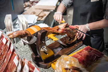 the butcher cuts the jamon into thin pieces