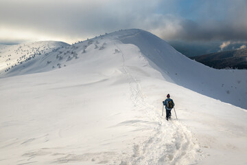 tourist with backpack hiking in winter mountains