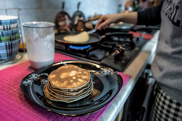 woman in the kitchen frying pancakes