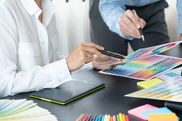 Graphic designer or creative working together coloring using graphics tablet and a stylus at desk...