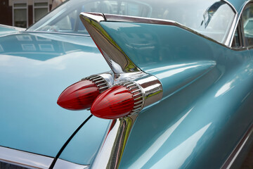 Green classic oldtimer car with red tail lights on tail fin with chrome elements. 