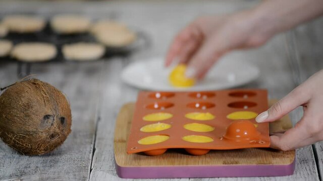 Hands taking orange filling out of a flexible silicone mold.