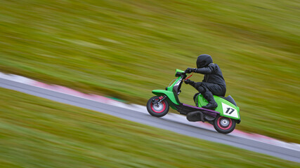 Fototapeta premium A panning shot of a racing scooter as it circuits a track.