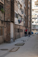 Old alley in the city of Barcelona, ​​there are some men are a ladder fixing the cables of the facade