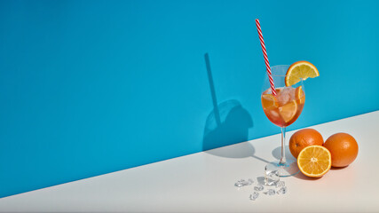 Fruit drink with ice and oranges on double white blue background with shadow. Cocktail. Orange juice