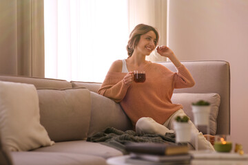 Beautiful young woman with cup of tea relaxing at home. Cozy atmosphere
