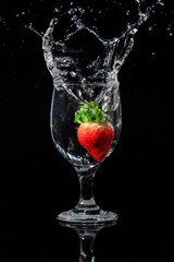 The strawberry falls into a glass of water
