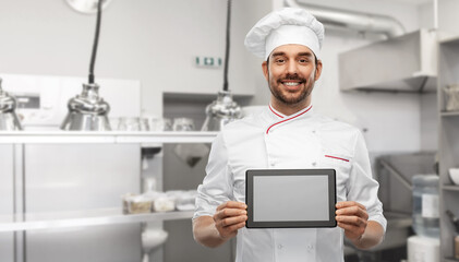 Naklejka na ściany i meble cooking, culinary and people concept - happy smiling male chef in toque showing tablet pc computer over restaurant kitchen background