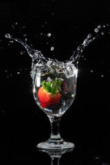 The strawberry falls into a glass of water

