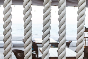 Closeup of strong string white ropes on background sea and deck. Abstract sailor marine backdrop. Textured twisted vertically fiber line