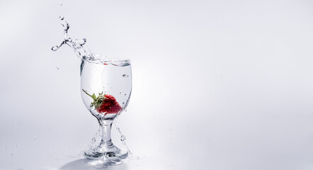 The strawberry falls into a glass of water
