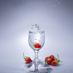 The strawberry falls into a glass of water
