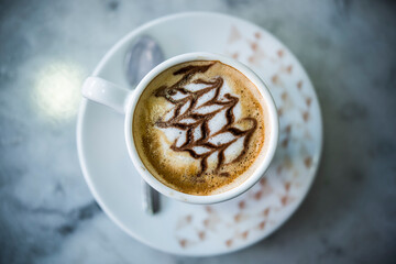 coffee with milk, with drawing in a white cup on the table