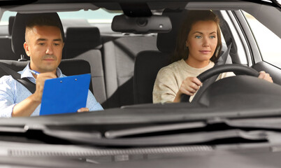 driver courses, exam and people concept - young woman and driving school instructor with clipboard in car