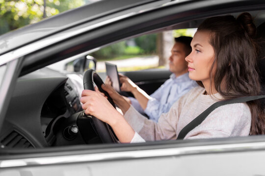 driver courses and people concept - car driving school instructor teaching young woman to drive