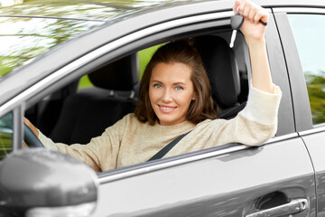 driving, safety and people concept - young woman or female driver sitting in car and showing key