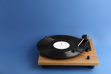 Turntable with vinyl record on blue background. Space for text