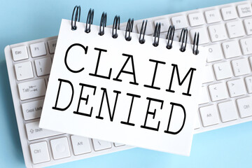 CLAIM Denied. time to restart. text on white notepad paper on white keyboard