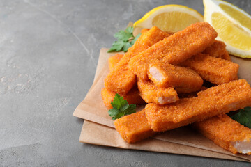 Fresh breaded fish fingers served on grey table, space for text