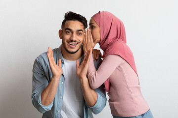 Gossips Concept. Muslim Woman In Hijab Whispering Secret To Her Surprised Boyfriend