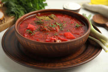 Stylish brown clay bowl with Ukrainian borsch served on white wooden table