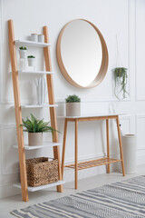 Console table with shelving unit and mirror on white wall in hallway. Interior design