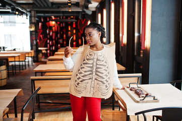 African woman eat spicy hot grilled spare ribs on wooden desk.