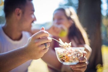 Couple in the park having break and eating healthy meal.