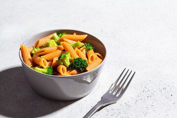 Red lentil pasta with broccoli in gray bowl. Healthy vegan pasta with vegetables.