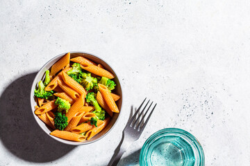 Red lentil pasta with broccoli in gray bowl, top view, copy space. Healthy vegan pasta with vegetables.